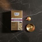 RoC Retinol Correxion Night Serum Capsules gold box on dark marble with pearl capsule and gold dish.