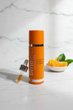 Premium orange skincare serum bottle resting on an immaculate white marble countertop in soft natural lighting