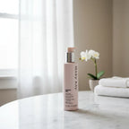 Light filled bright room shot of Mary Kay skincare body cream pump bottle standing tall on white vanity surface