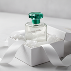 Lifestyle image — clear glass perfume bottle on white tissue paper in open gift box with white ribbon, elegant feminine gifting photography for visual context only