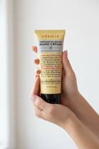 Adamia hand cream held in woman's hands with smooth moisturized skin