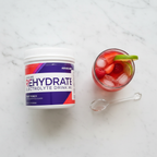 AdvoCare Rehydrate Fruit Punch tub on marble with fruit punch glass and ice – More4less Outlet