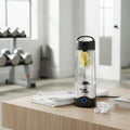 Magic Bullet Portable Blender on wooden coffee table in fitness studio with folded towel and wireless earbuds for gym routine