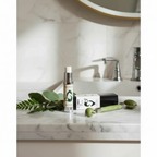 Vixen Skincare Botanical Eye Cream on marble countertop with botanicals and jade roller