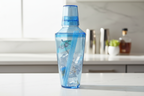 Vibrant translucent powder blue cocktail shaker on clean white kitchen counter with soft natural light