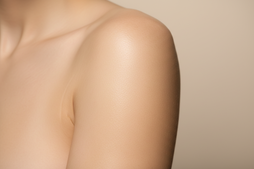 Close-up of smooth firm hydrated skin on woman's arm and shoulder with natural glow - anti-aging body lotion result