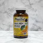 MegaFood Men's 40+ One Daily multivitamin amber glass bottle in soft natural window light on white quartz countertop – More4less Outlet