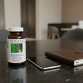 Innate Response Men Over 40 Multivitamin on black granite office desk with metallic smartphone and leather daily planner