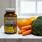 MegaFood Women's 55+ Advanced Multivitamin amber glass bottle beside fresh organic oranges carrots and broccoli on white marble – More4less Outlet