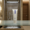 ZO Medical Vitascrub on frosted glass shelf in luxury spa restroom with waterfall background