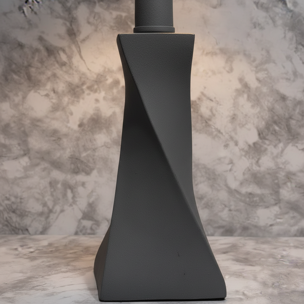 Soft warm lighting detail on modern twisted stone gray lamp base showing matte textured finish