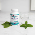 NutriCology L-Methionine bottle on marble with green leaves and glass of water – More4less Outlet