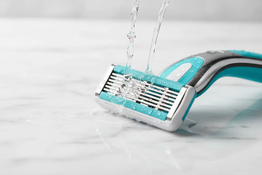 Water droplets splashing gently against a high-quality 5-blade women's razor cartridge on white marble