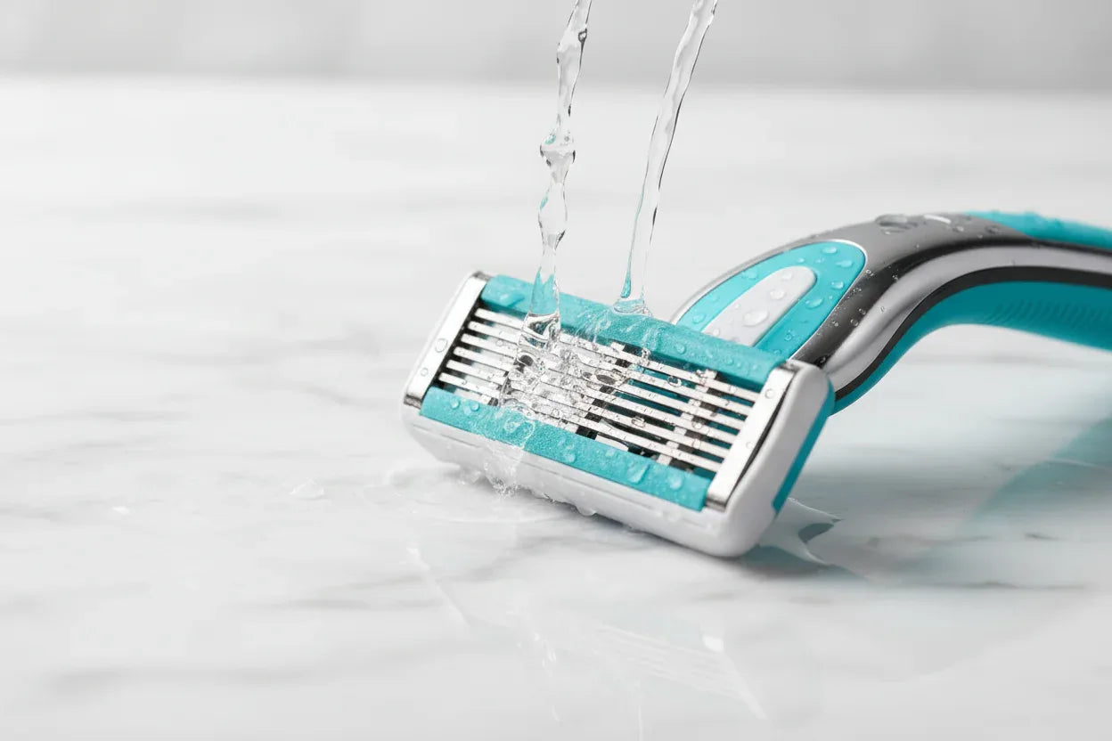 Water droplets splashing gently against a high-quality 5-blade women's razor cartridge on white marble