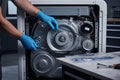 Technician installing new drive belt inside a residential laundry appliance