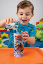 Child pouring water into Jurassic World Dino Reveal canister toy for water reveal moment in bright playroom — More4less Outlet