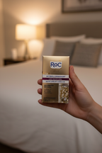 RoC Retinol Correxion Night Serum Capsules held in hand against soft bedroom nighttime background.