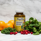 MegaFood Women's One Daily Multivitamin amber glass bottle beside fresh organic oranges cranberries and leafy greens on white marble – More4less Outlet