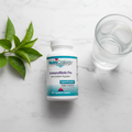 NutriCology ImmunoBiotic Pro bottle on marble with green leaves and glass of water – More4less Outlet