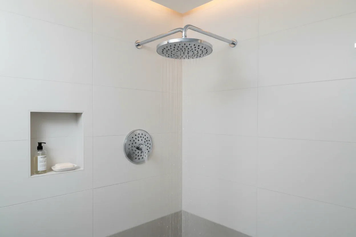 Modern spa-style bathroom with polished chrome round shower head and white tile walls