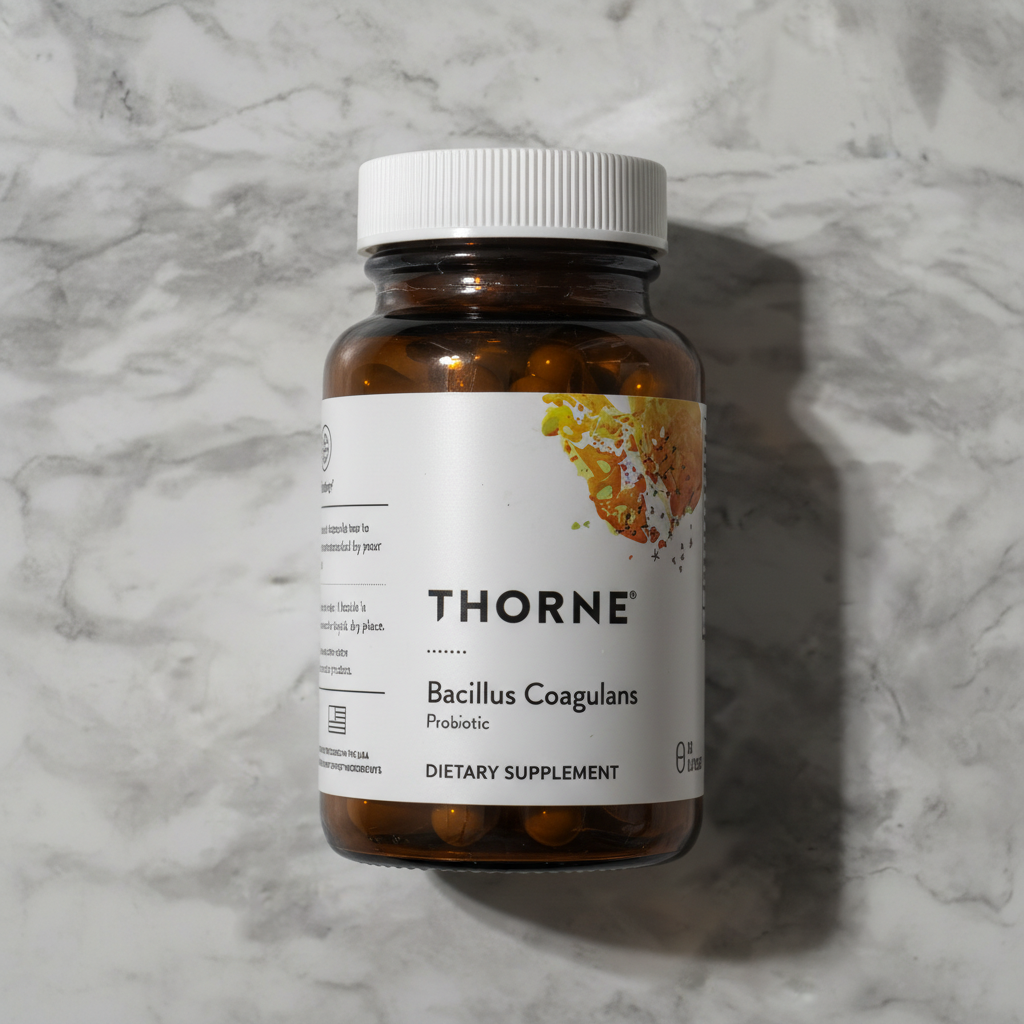 Thorne Bacillus Coagulans Probiotic amber glass bottle centered on neutral marble background - studio shot