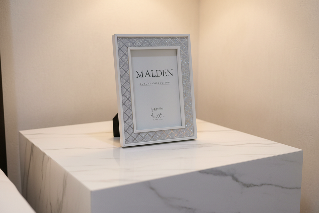 Elegant silver glitter lattice picture frame on a minimalist white marble nightstand with warm ambient lighting