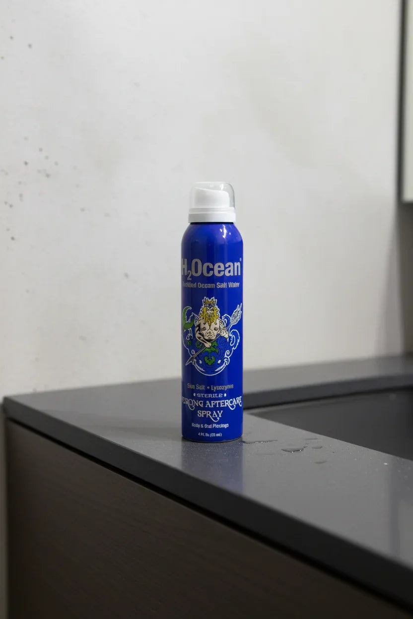 Blue aerosol bottle sitting on a minimalist dark slate bathroom vanity in soft clean lighting