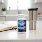 One A Day Men's Complete Multivitamin bottle on white quartz kitchen island with health-track log book and metallic fitness tumbler