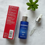 Olay Hyaluronique Hydratant Sérum flat lay on white linen with glass dropper, green plant, and water droplets