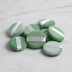 Sage green mint velvet mini powder puffs resting on white marble tile beauty display — More4less Outlet