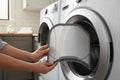 Person sliding a new lint filter into a dryer opening in a clean modern laundry room