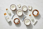 Professional flat lay of women's personal care products with a coconut theme on white marble with fresh coconut halves