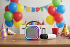 Bytech Mini Karaoke Speaker and wireless microphone on a table at a colorful kids birthday party with balloons in background