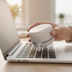 Close-up of a white circular handheld mini desktop vacuum cleaning between laptop keyboard keys