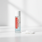 Rodan + Fields ESSENTIALS eye makeup remover bottle beside plain white cotton rounds on a clean vanity