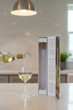 White wine being poured from bottle with Corkcicle Air aerator spout into wine glass, frost visible on chiller device