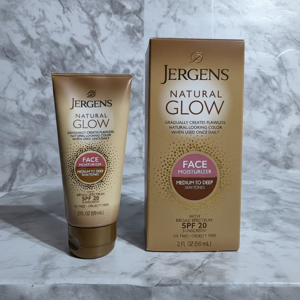 Close-up of Jergens Natural Glow gold gradual tanning face lotion squeeze tube and box on white marble, bright studio lighting