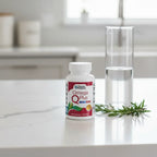 Doctors' Preferred Omega Q Plus bottle on white quartz kitchen island with clear water carafe and fresh rosemary sprigs