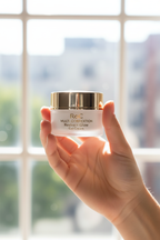RoC Multi Correxion Revive + Glow Gel Cream held in hand near bright sunny window lifestyle photo.