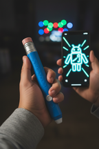 Close-up of Pictionary Air 2 blue drawing pen held in hand with glowing digital drawing on smartphone screen — More4less Outlet