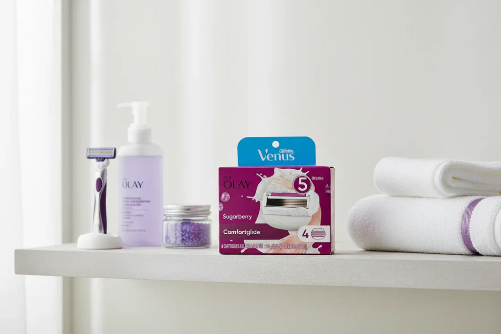 Organized shelf of personal care essentials including razor refills in a bright minimalist bathroom setting with purple accents