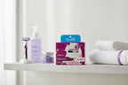 Organized shelf of personal care essentials including razor refills in a bright minimalist bathroom setting with purple accents