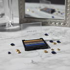 Mary Kay Eye Color Palette Rock the Runway open compact on a white marble vanity showing five metallic eyeshadow strips — gold, bronze, silver, cobalt blue, midnight navy — with dramatic studio lighting, blurred mirror, and scattered gold and navy gemstones