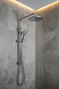 Grohe Rainshower polished chrome wall mount shower arm installed on grey stone tile with large rain shower head and water falling