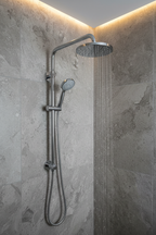 Grohe Rainshower polished chrome wall mount shower arm installed on grey stone tile with large rain shower head and water falling