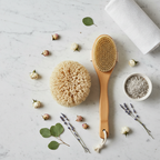 Flat-lay of natural spa accessories with sea sponge, bamboo brush, and floral accents on marble