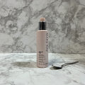 Professional studio shot of Mary Kay TimeWise Body beauty cream pump bottle on clean light marble background