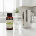 Nature's Sunshine Cordyceps bottle on white quartz kitchen island with fresh glass of sparkling water and stainless steel water pitcher