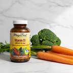 MegaFood Vitamin D3 amber glass bottle beside fresh organic broccoli and carrots on white marble – More4less Outlet