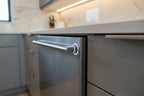 Close up of a stainless steel dishwasher door being firmly locked shut